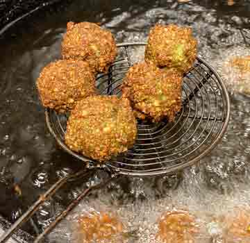 5 gerade frittierte Falafel auf einer Schöpfkelle - gerade fertig für die nächste Habibi-Platte